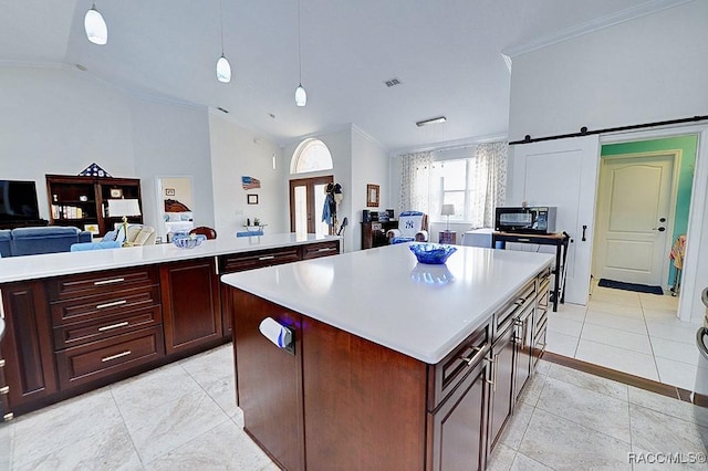 kitchen with lofted ceiling, a barn door, open floor plan, light countertops, and a center island