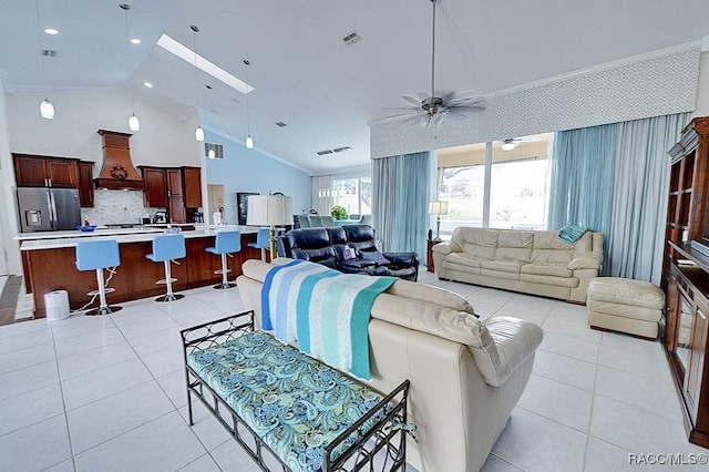 living room featuring light tile patterned floors, ceiling fan, lofted ceiling with skylight, and crown molding