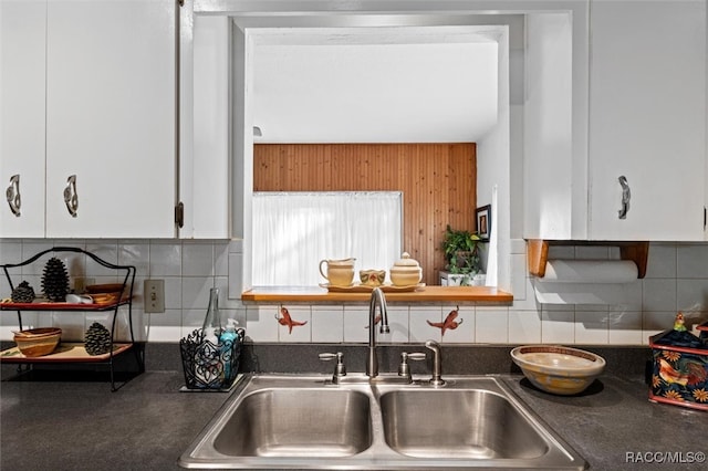 kitchen featuring decorative backsplash, white cabinetry, and sink