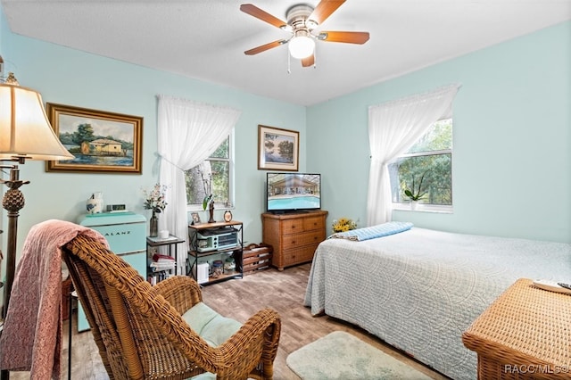 bedroom featuring multiple windows, light hardwood / wood-style floors, and ceiling fan