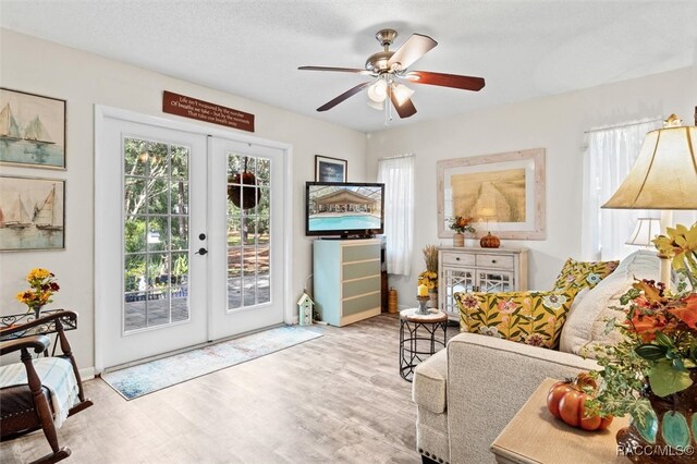 sitting room featuring a textured ceiling, ceiling fan, light hardwood / wood-style flooring, and french doors