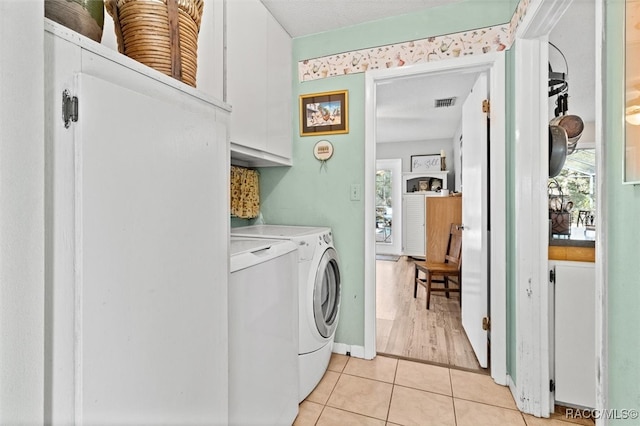 clothes washing area with cabinets, light tile patterned floors, and separate washer and dryer