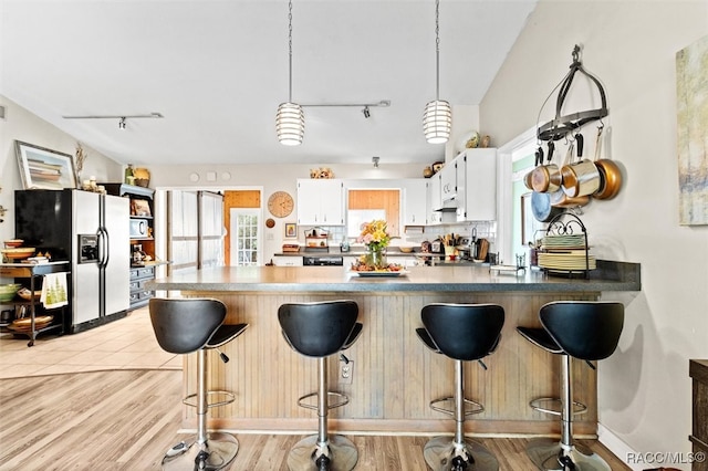 kitchen featuring pendant lighting, a breakfast bar, backsplash, white cabinets, and stainless steel fridge with ice dispenser