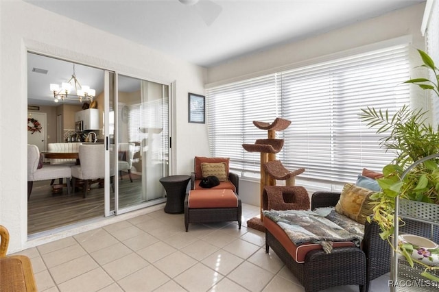 sitting room featuring ceiling fan with notable chandelier and light tile patterned floors