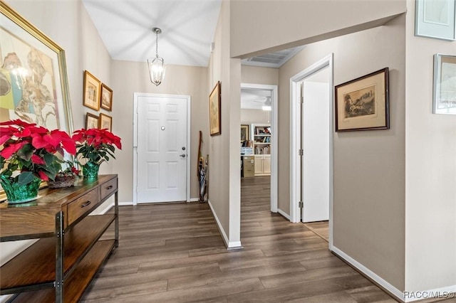 entryway with an inviting chandelier and dark wood-type flooring