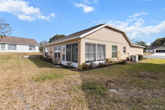 back of property featuring a sunroom and a lawn