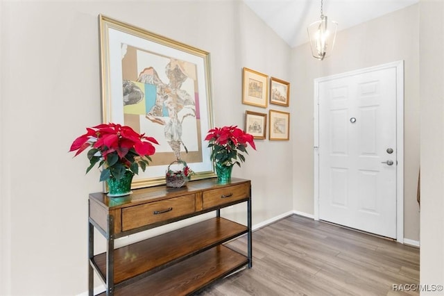 foyer entrance with hardwood / wood-style flooring, lofted ceiling, and an inviting chandelier