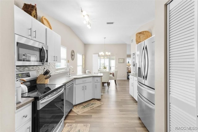 kitchen featuring sink, light wood-type flooring, appliances with stainless steel finishes, decorative light fixtures, and white cabinetry