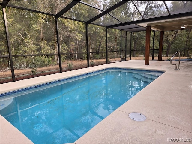 view of pool with glass enclosure and a patio