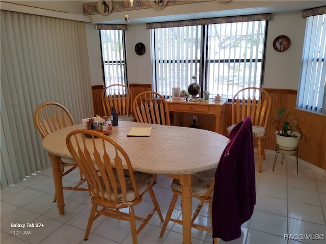 dining space featuring plenty of natural light, light tile patterned flooring, and wooden walls