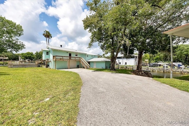 11615 N Caribee Pt, Inglis, FL 34449 - view of front of home with stairs, driveway, a garage, a front lawn, and a deck with water view