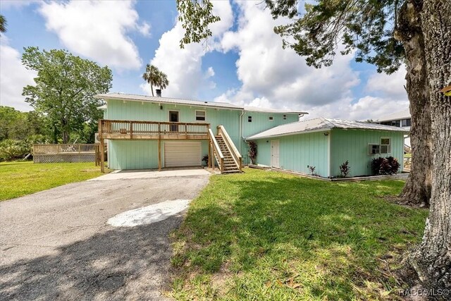 11615 N Caribee Pt, Inglis, FL 34449 - view of front of property with asphalt driveway, stairway, a front lawn, an attached garage, and a wooden deck