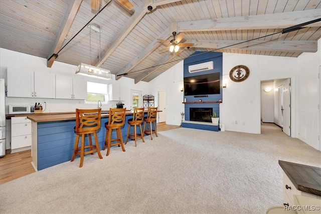 11615 N Caribee Pt, Inglis, FL 34449 - kitchen with white microwave, butcher block countertops, light colored carpet, a breakfast bar, and wood ceiling with exposed beams