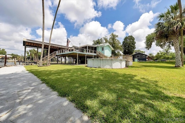 11615 N Caribee Pt, Inglis, FL 34449 - rear view of house with stairway, a lawn, an outdoor pool, and a deck