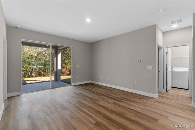 spare room featuring visible vents, wood finished floors, washer / dryer, and baseboards