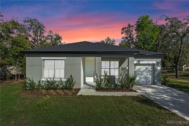 view of front facade featuring stucco siding, a shingled roof, an attached garage, driveway, and a front lawn