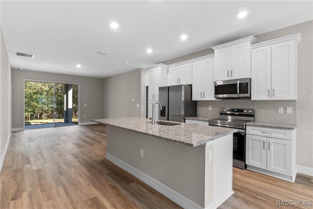 kitchen with white cabinets, a kitchen island with sink, stainless steel appliances, and a sink