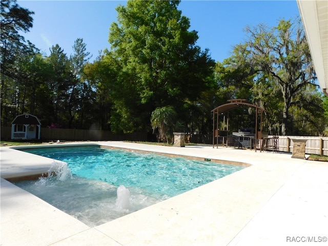 view of swimming pool featuring pool water feature, a patio, and a shed