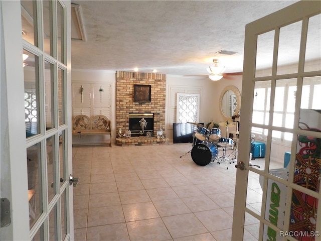 tiled living room with french doors, a textured ceiling, and a brick fireplace