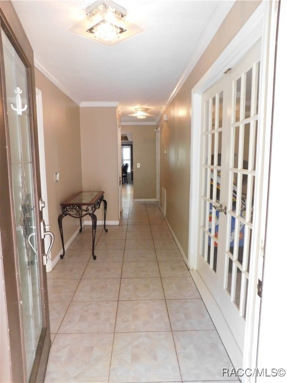 corridor with french doors, crown molding, and light tile patterned flooring