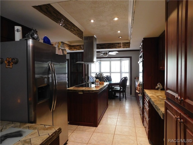 kitchen with ceiling fan, stainless steel fridge with ice dispenser, island exhaust hood, a tray ceiling, and light tile patterned flooring