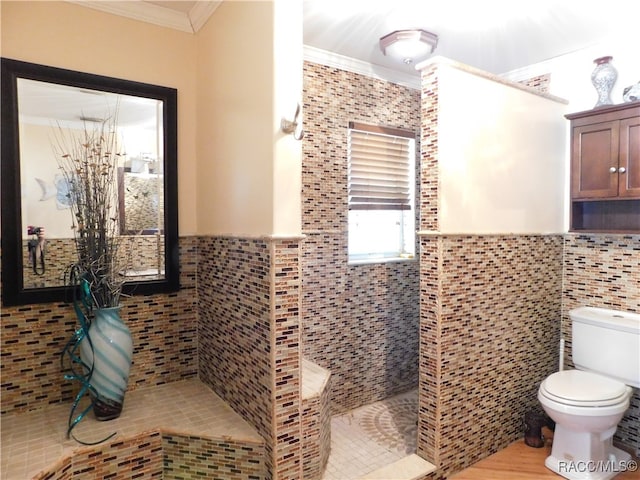 bathroom with toilet, crown molding, and tile walls