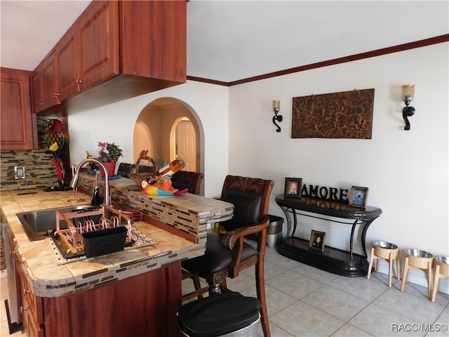 kitchen with tile counters, sink, decorative backsplash, light tile patterned floors, and ornamental molding