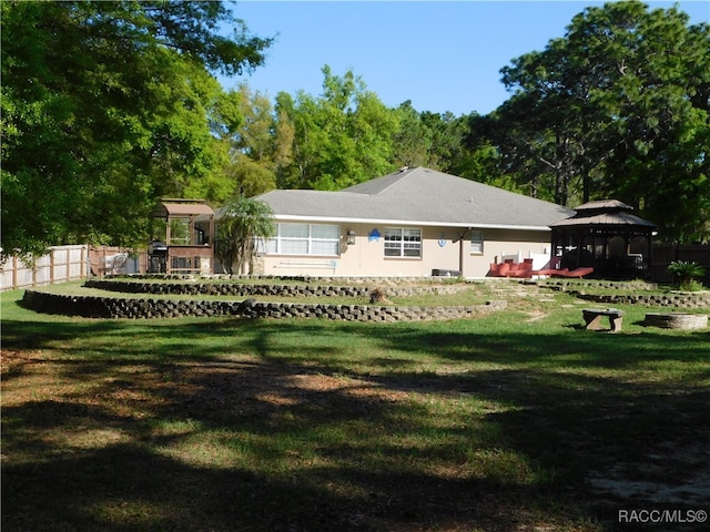 rear view of house featuring a gazebo and a lawn