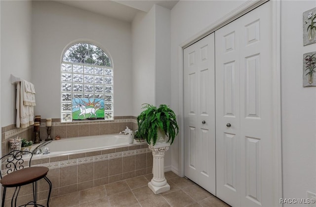 bathroom with tile patterned floors and tiled tub