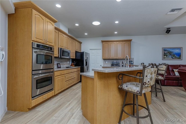 5281 W Cisco St, Beverly Hills, FL 34465 - kitchen with appliances with stainless steel finishes, a breakfast bar area, light wood-type flooring, decorative backsplash, and recessed lighting