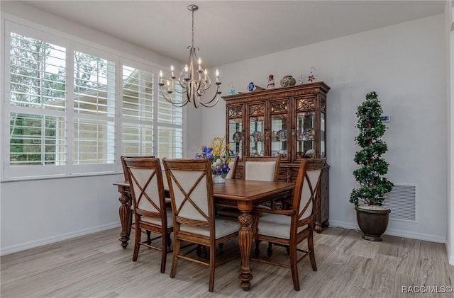 dining space with light hardwood / wood-style flooring and a chandelier