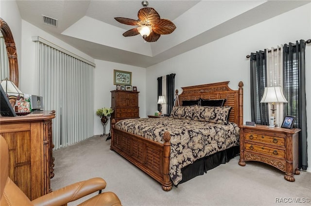 bedroom with a tray ceiling, ceiling fan, and light colored carpet