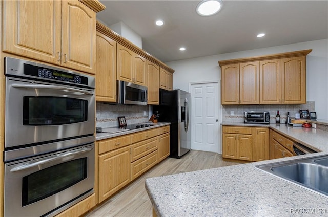 kitchen with light brown cabinetry, light wood-type flooring, backsplash, stainless steel appliances, and sink