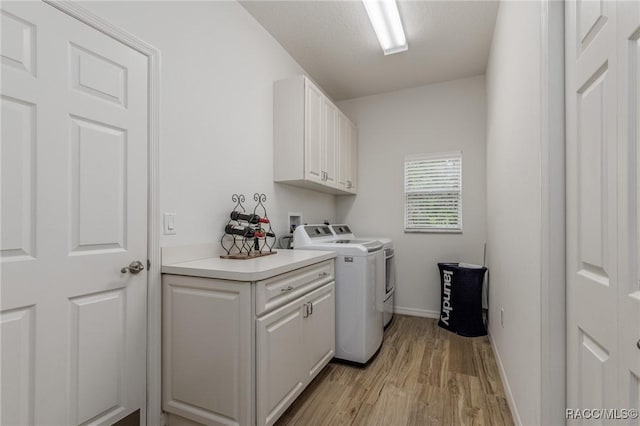 laundry room featuring cabinets, light hardwood / wood-style flooring, and washer and dryer