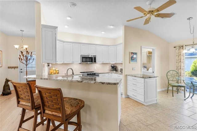 kitchen with appliances with stainless steel finishes, backsplash, light stone counters, and pendant lighting