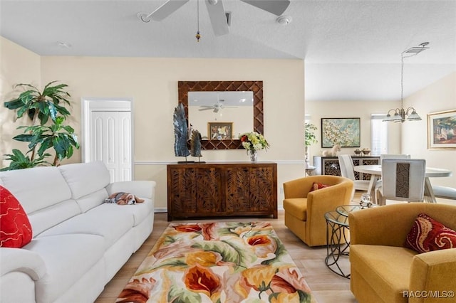 living room with lofted ceiling, a textured ceiling, light hardwood / wood-style flooring, and a notable chandelier