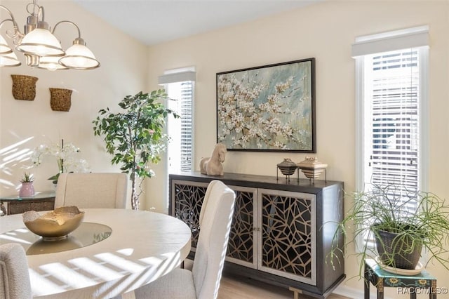 dining space featuring a wealth of natural light, wood-type flooring, and an inviting chandelier