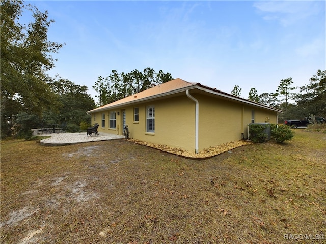 view of home's exterior featuring central AC, a yard, and a patio