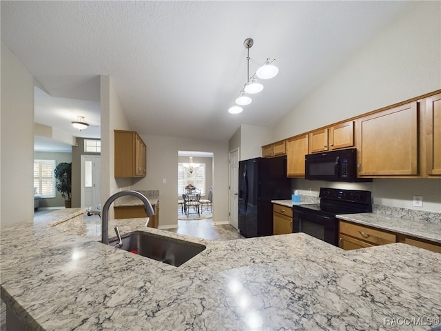 kitchen featuring vaulted ceiling, black appliances, sink, light stone counters, and kitchen peninsula