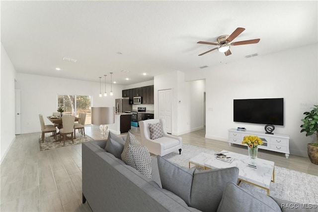 living area featuring a ceiling fan, light wood-type flooring, baseboards, and recessed lighting