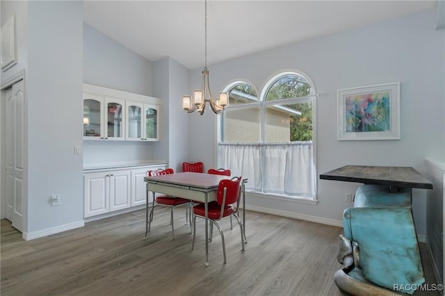 dining space featuring light hardwood / wood-style floors, vaulted ceiling, and an inviting chandelier