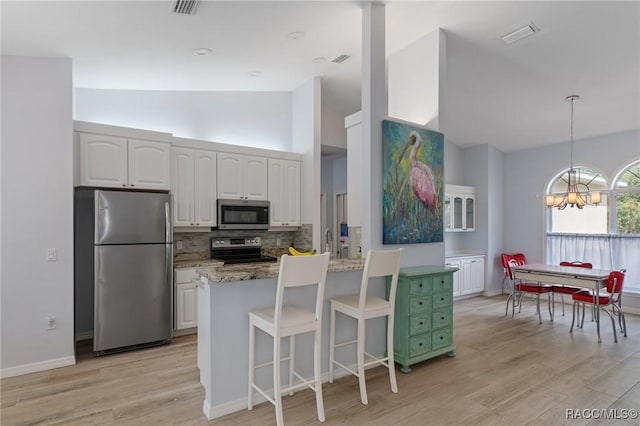 kitchen with appliances with stainless steel finishes, white cabinets, stone countertops, and decorative backsplash