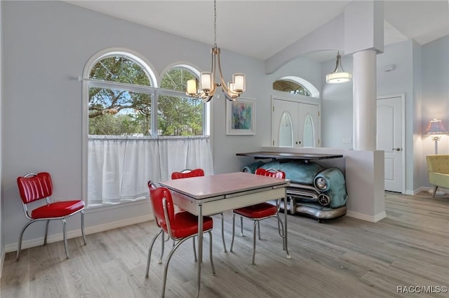 dining area with light wood-type flooring, vaulted ceiling, and a chandelier