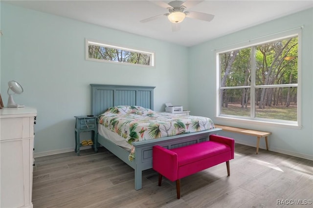 bedroom featuring multiple windows, hardwood / wood-style floors, and ceiling fan