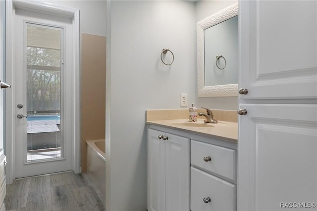 bathroom with hardwood / wood-style flooring, vanity, and a bath