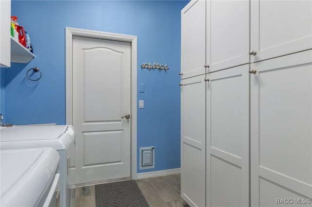 clothes washing area featuring cabinets, washer and clothes dryer, and light hardwood / wood-style flooring