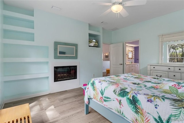 bedroom featuring ceiling fan, light hardwood / wood-style floors, and connected bathroom