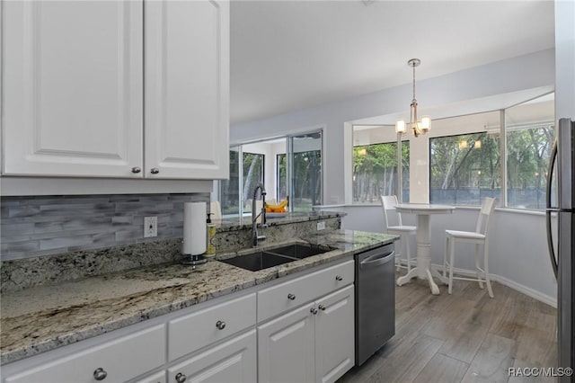 kitchen featuring white cabinets, stainless steel dishwasher, decorative light fixtures, backsplash, and sink