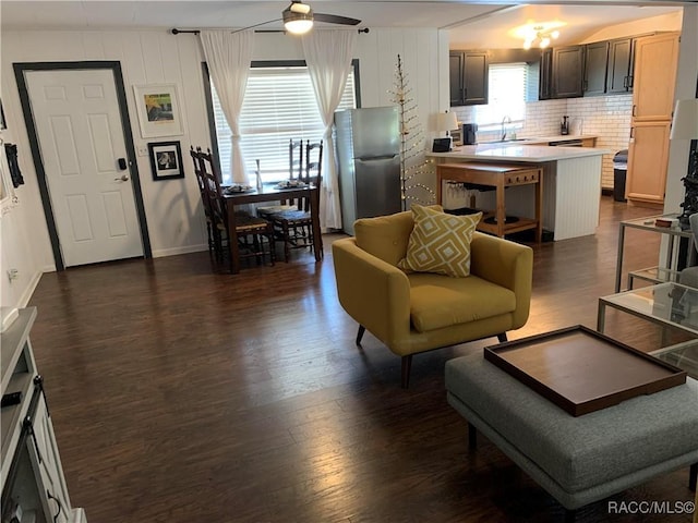 living room featuring dark wood-type flooring, ceiling fan, and baseboards