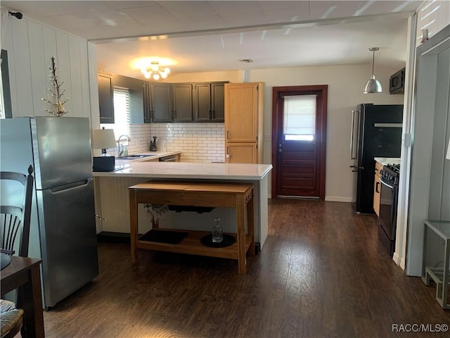 kitchen featuring pendant lighting, light countertops, a sink, a peninsula, and black appliances